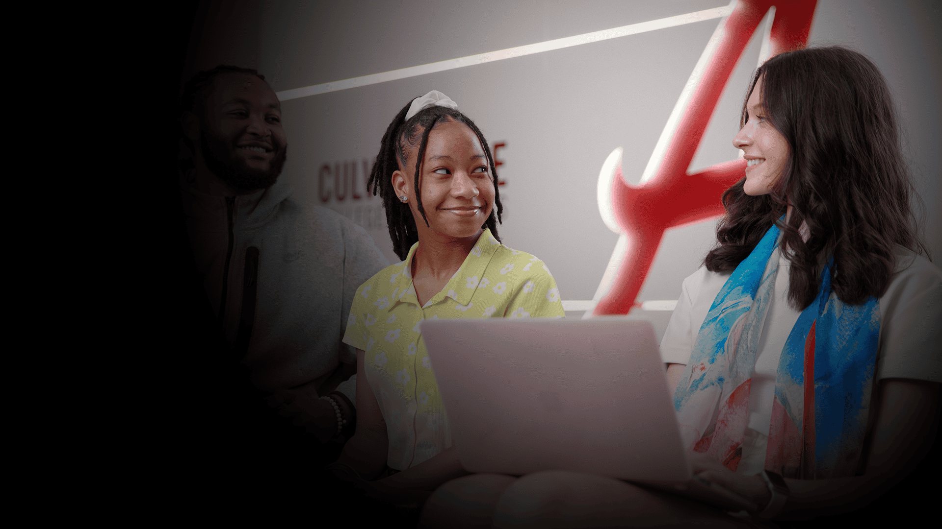 Students sitting and smiling at each other while studying on a laptop