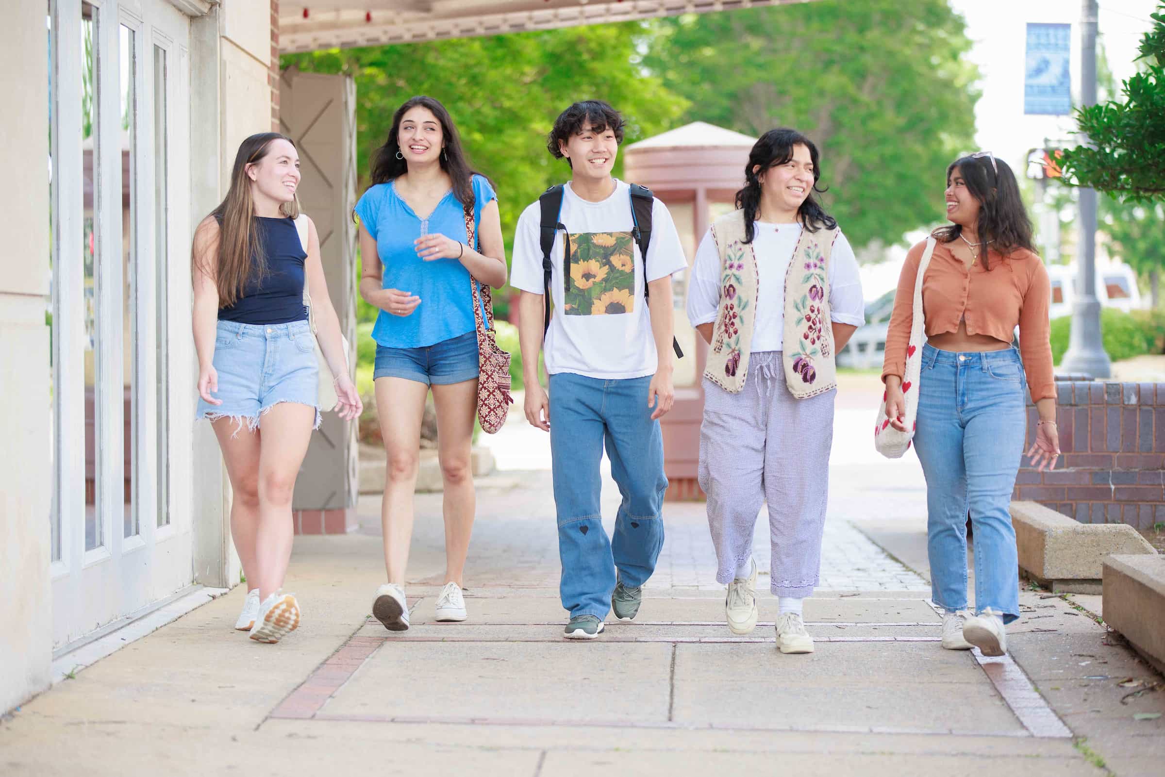 5 students walking side-by-side in downtown Tuscaloosa