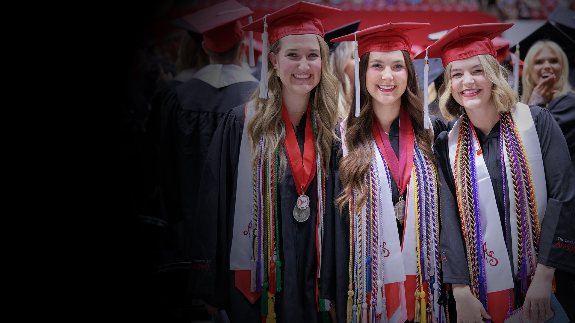 group of graduates smiling at commencement in cap in gown
