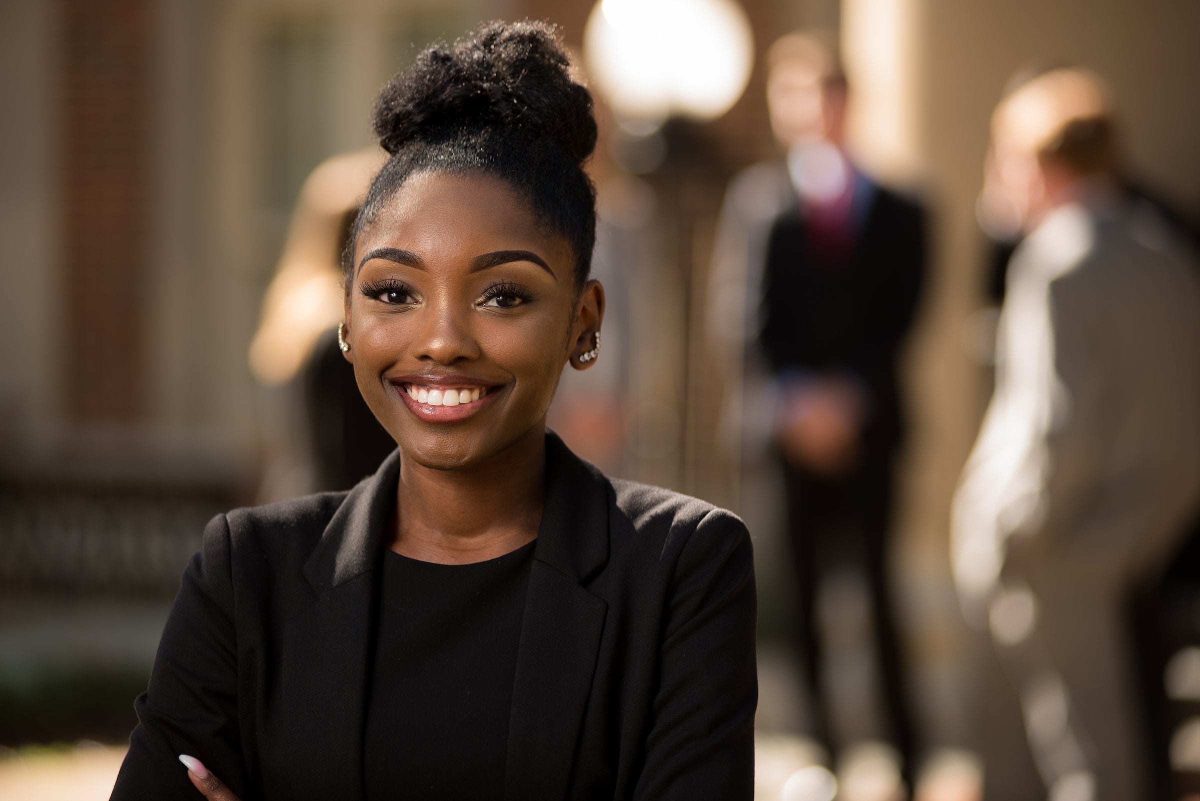 Female student in business attire posing in front of fellow students