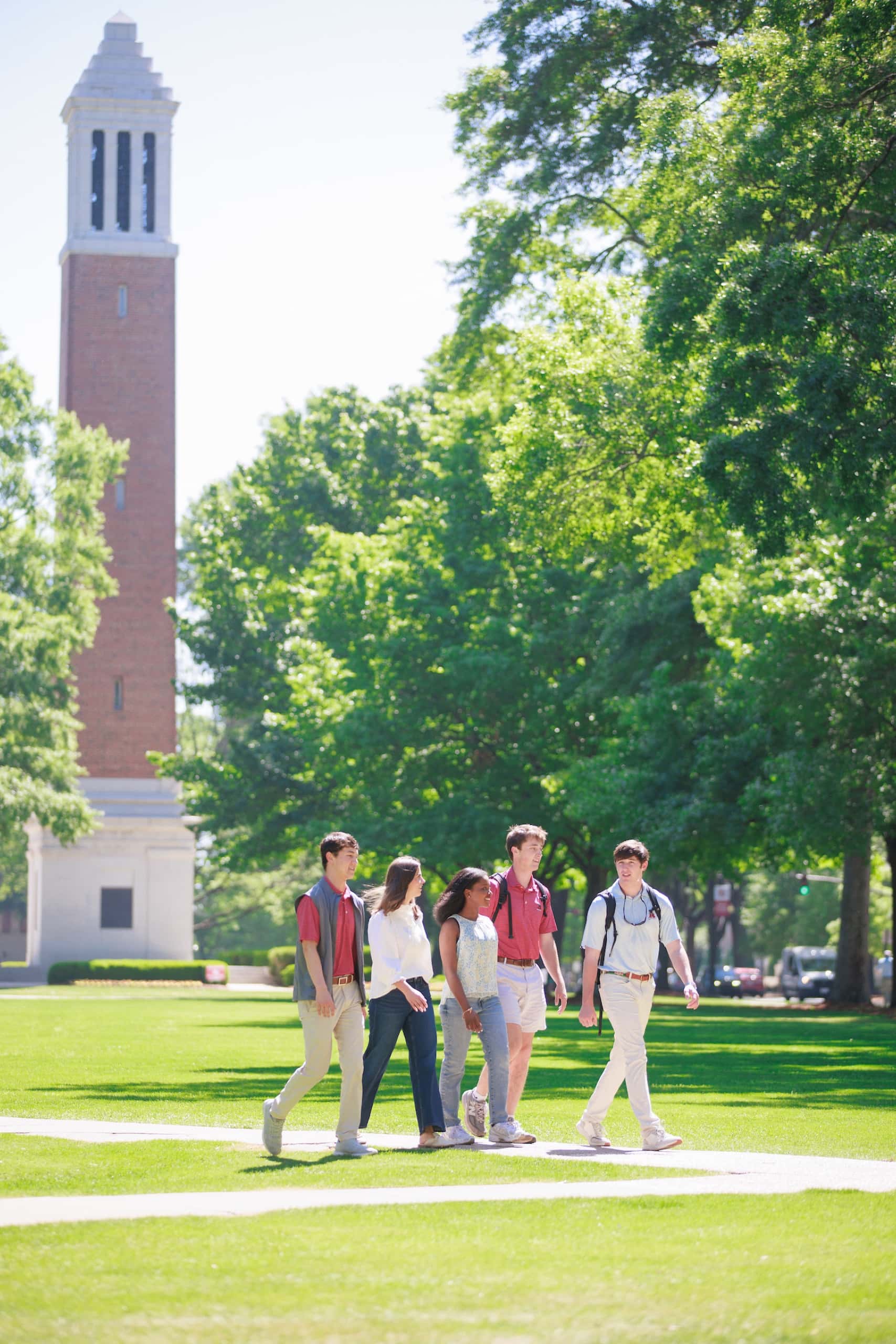 Five students walk along a Quad pathway past Denny Chimes on a sunny day.