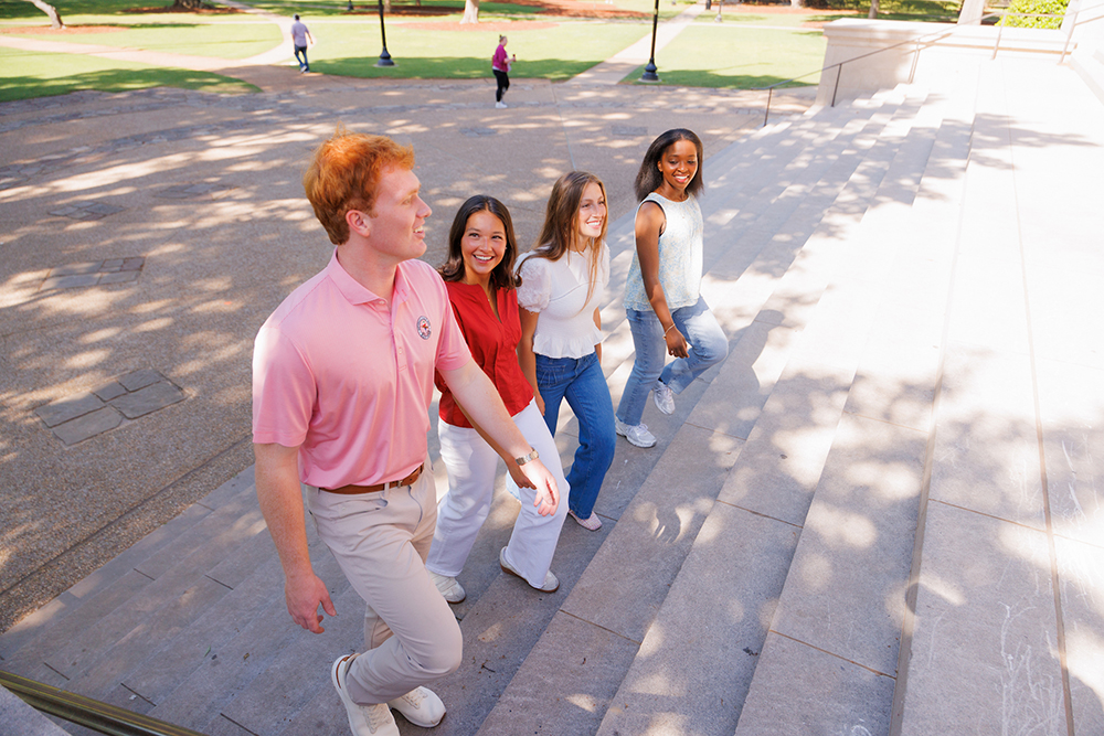 A group of smiling students ascend the stairs to the library.