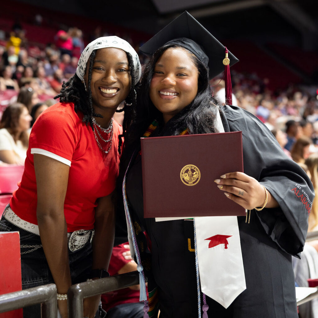 A UA graduate poses with her family member at a graduation ceremony